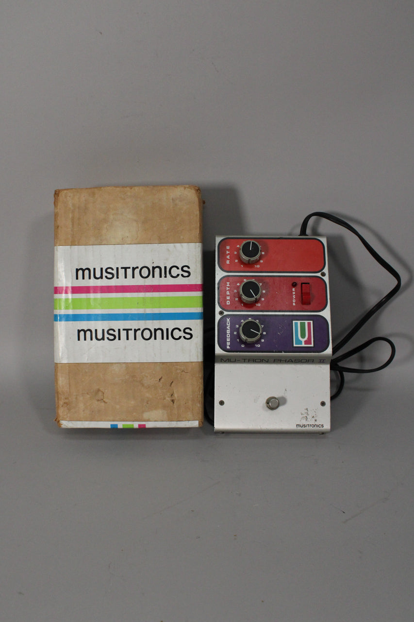 A vintage Mu-Tron Phasor II pedal with a white foot switch, three black control knobs on red and purple panels, and its original cardboard box.
