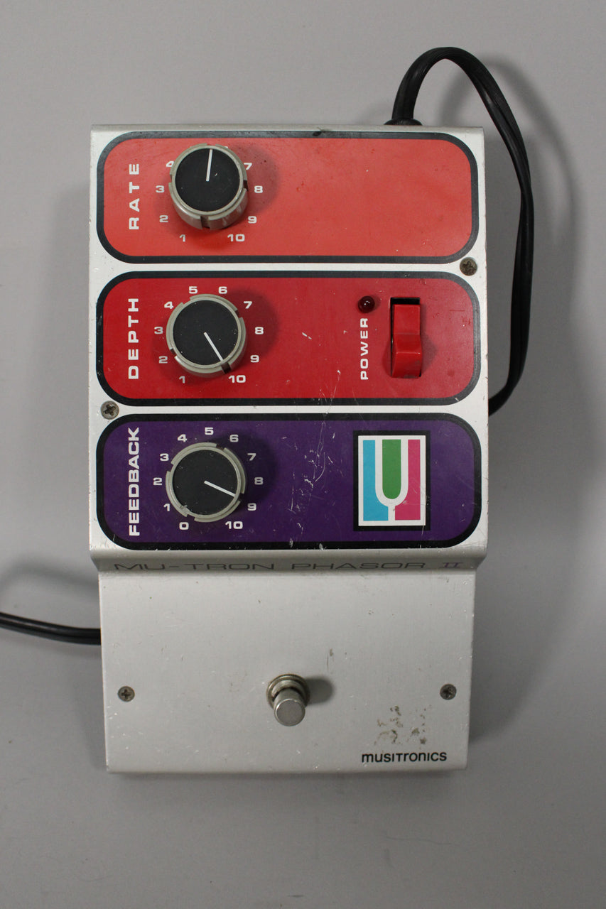 A top-down view of the silver pedal with red and purple control panels, three black knobs, a red power switch, and a foot switch.