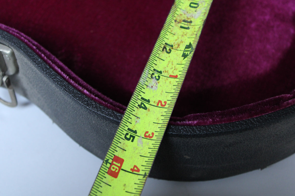 A tape measure shows the black case's purple velvet lining, with a metal latch visible on the left.