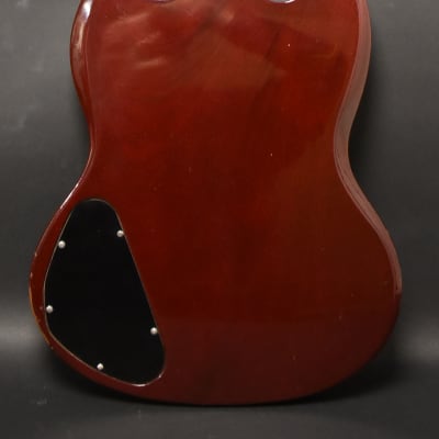 The cherry red SG back shows a black control cavity cover with six screws, and some finish wear on the lower horn.