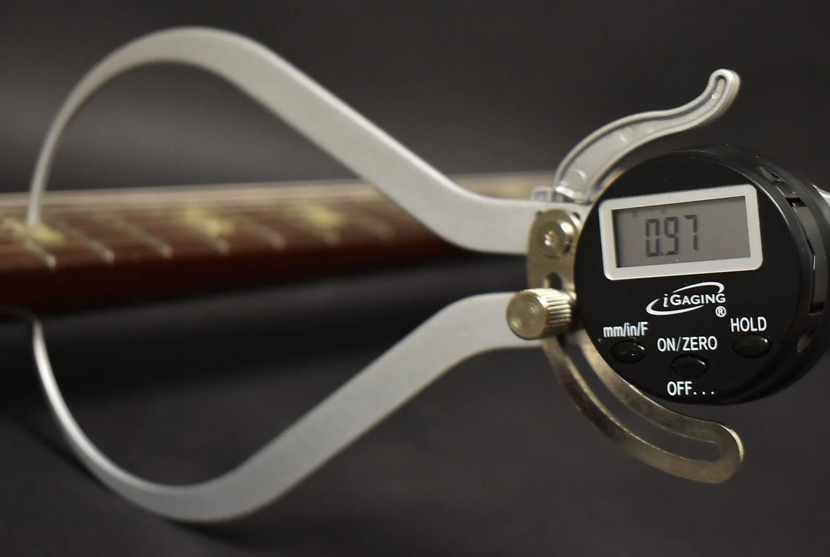 A digital caliper measures the neck thickness at the 1st fret, showing 0.97 inches, with light fretboard wear.