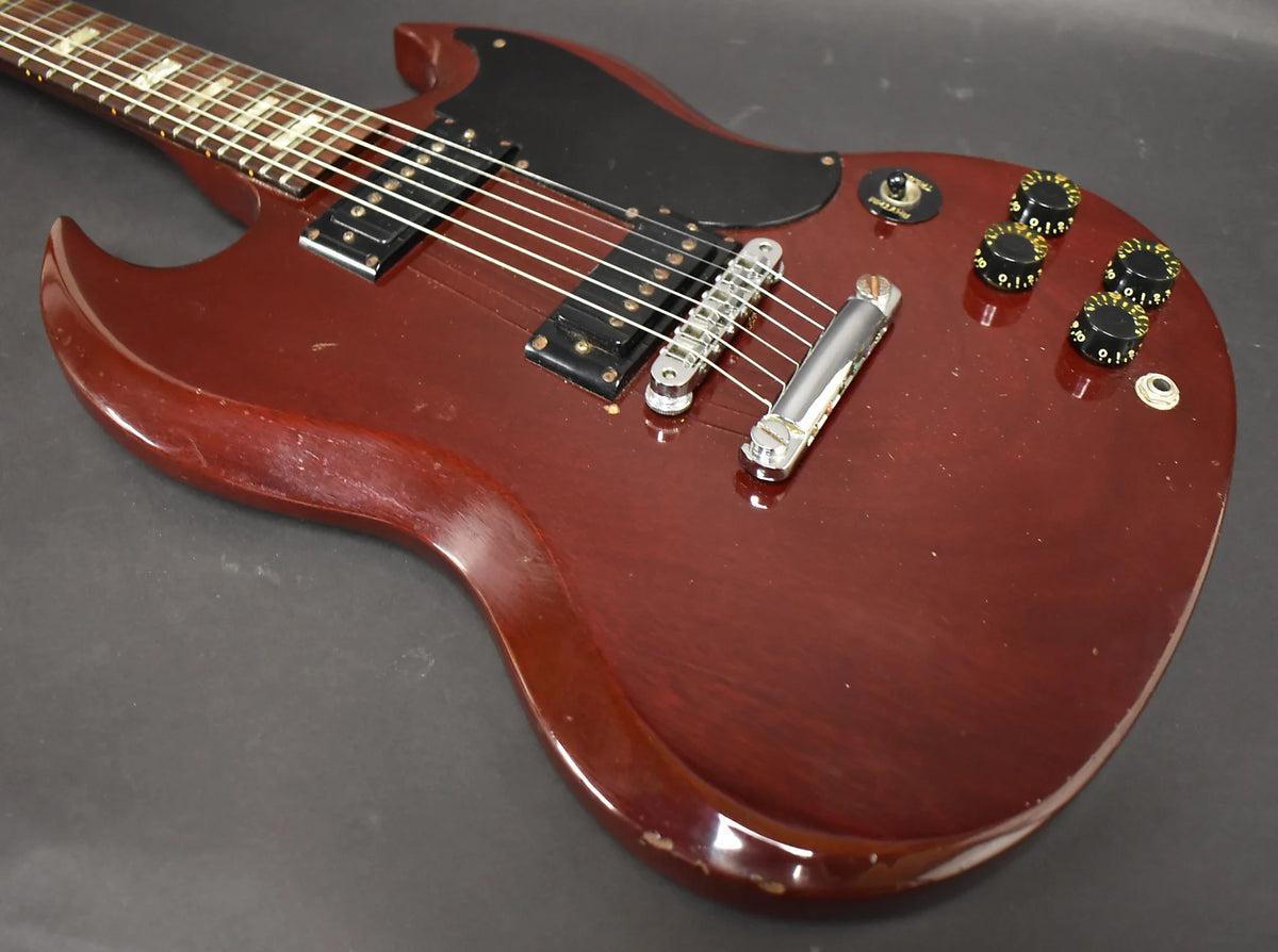 Cherry red SG body, angled from the neck, showing two humbuckers, a black pickguard, four black knobs, and a three-way switch.