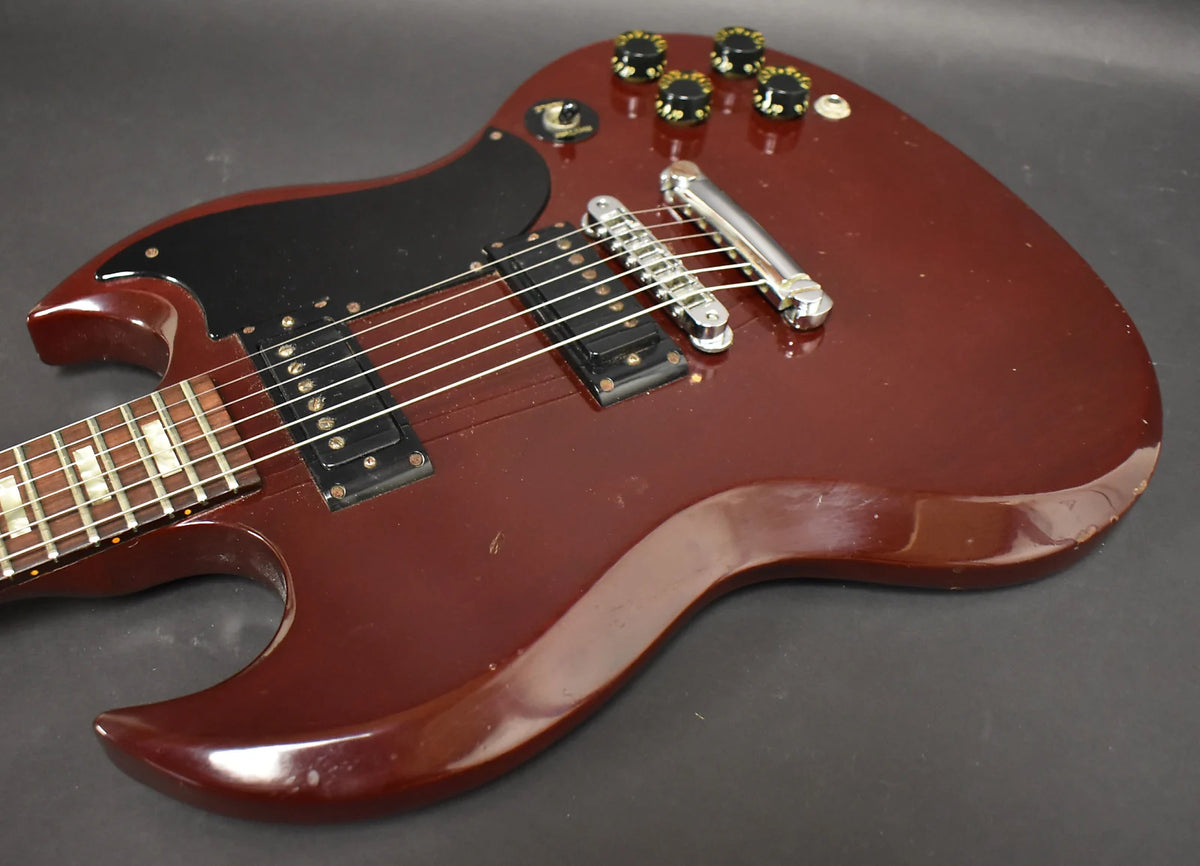 Close-up of a cherry red Gibson SG Special's body, showing the pickups, bridge, controls, and part of the fretboard.