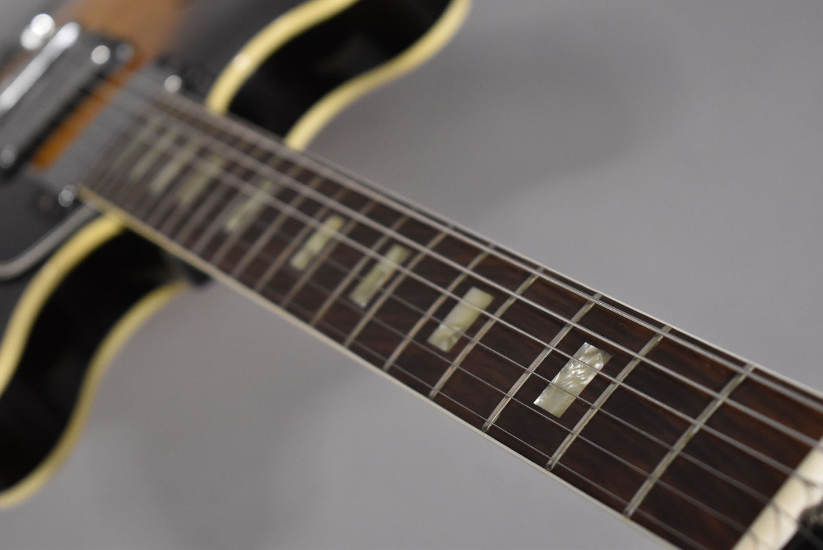 The guitar's dark fretboard with rectangular mother-of-pearl inlays is angled from the lower right to the upper left.