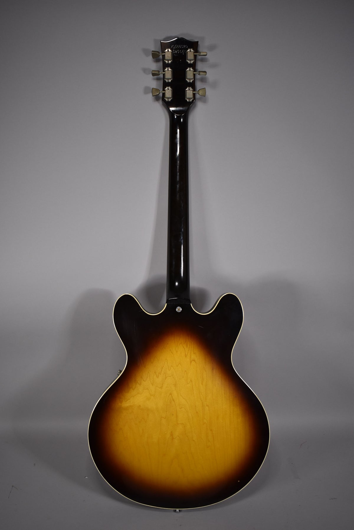 Full rear view of a sunburst semi-hollow guitar with a dark neck and headstock, showing light wear and six tuners.