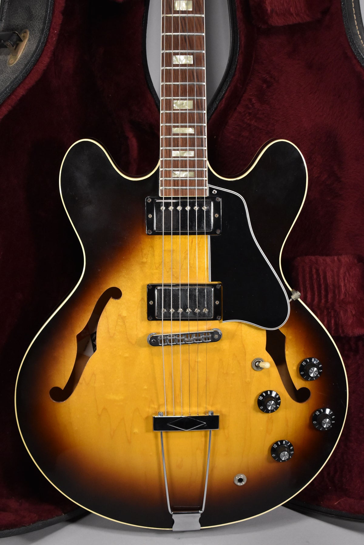 Sunburst semi-hollowbody electric guitar, angled from above, showing the body, f-holes, pickups, controls, and lower fretboard.