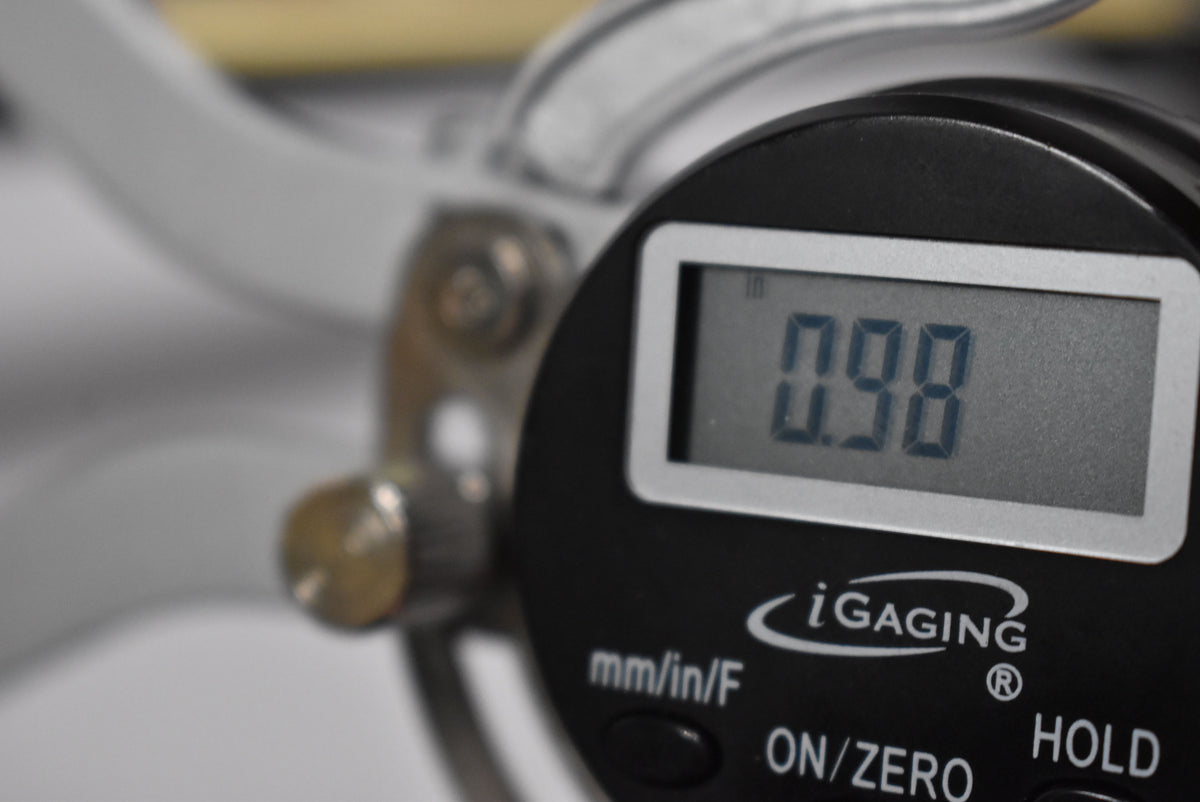 A digital caliper's screen shows a reading of 0.98 inches, with the iGaging logo and control buttons visible below.