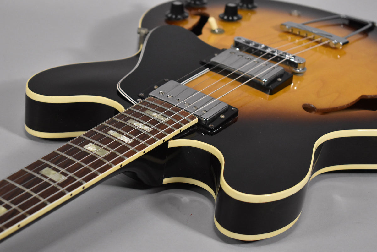Close-up of the sunburst body and neck, showing cream binding, chrome humbuckers, and trapezoid inlays on the fretboard.