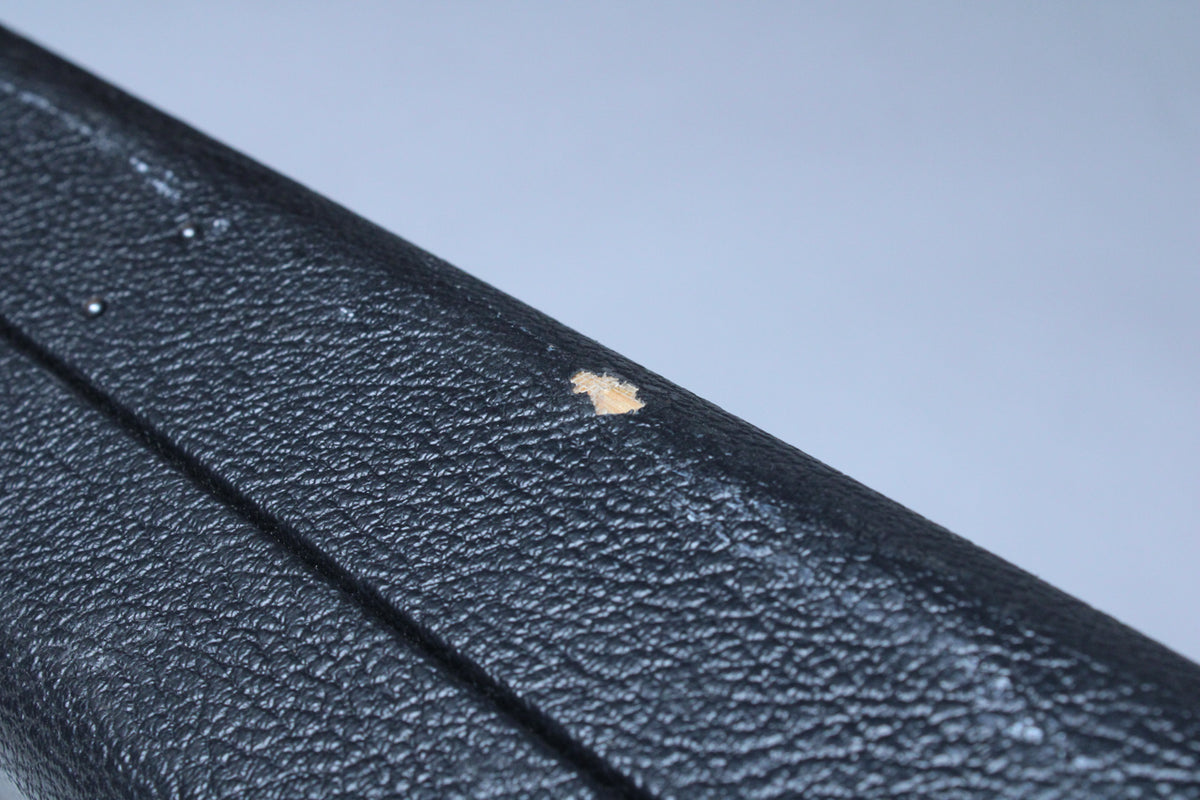 Close-up of the black textured case exterior, showing a small, light-colored chip in the finish near the top edge.