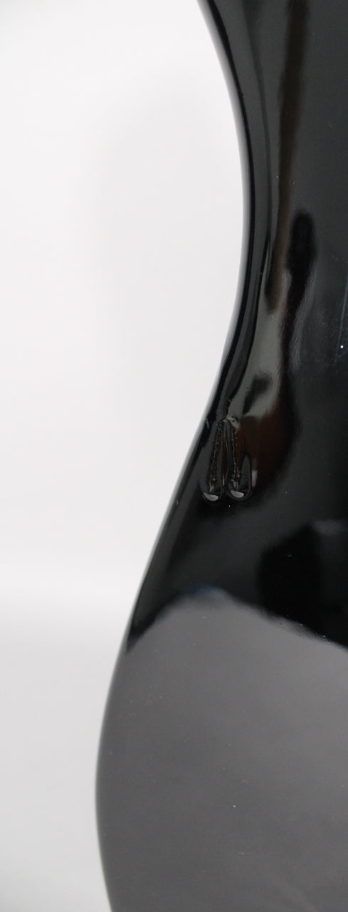 Close-up of the guitar's glossy black body, showing a small chip in the finish near the waist curve.