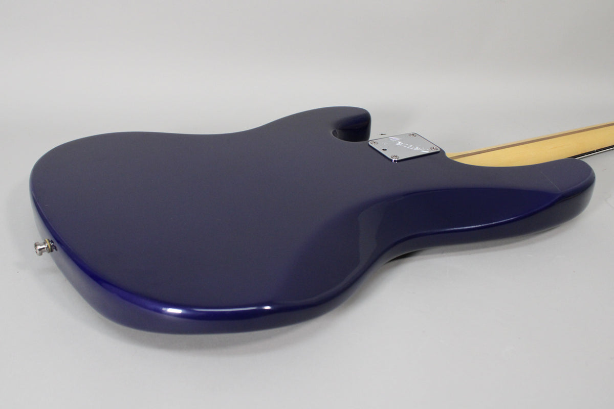 The midnight blue bass body, viewed from the back, shows a chrome neck plate and a strap button on the lower bout.
