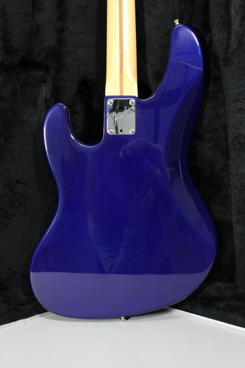 The back of a midnight blue bass guitar, showing the neck joint with a chrome plate and a scratch on the upper horn.