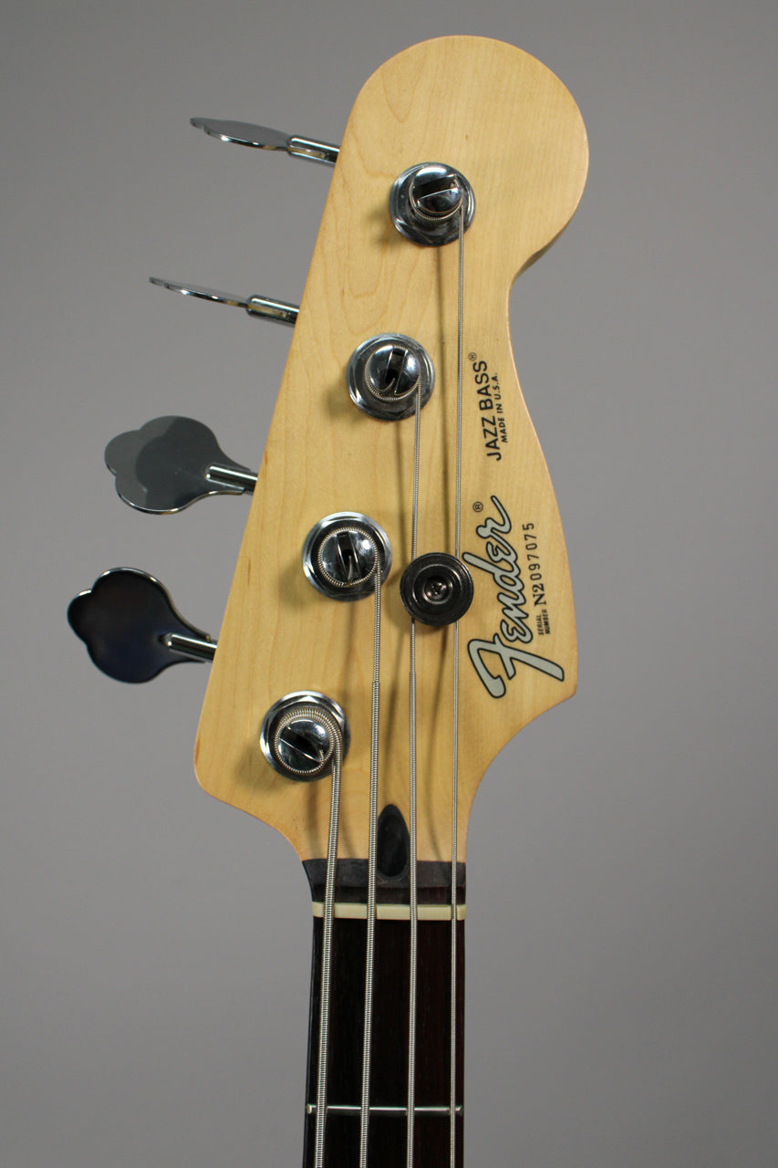 Close-up of the bass headstock, showing the light maple finish, chrome tuners, and dark rosewood fretboard.