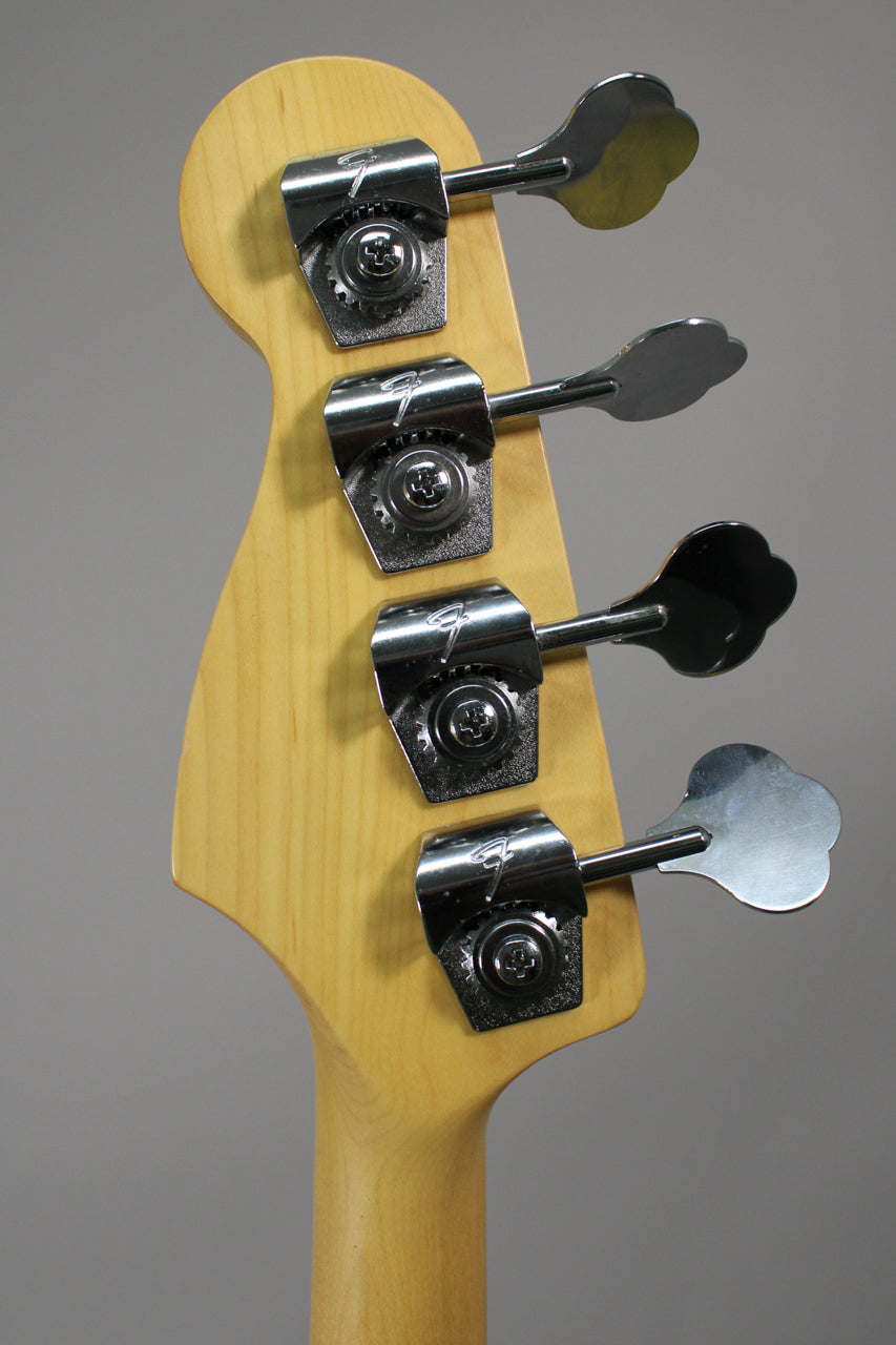 Rear view of the bass headstock and top of the neck, showing four chrome tuners with clover-leaf keys and light wear on the tuner casings.