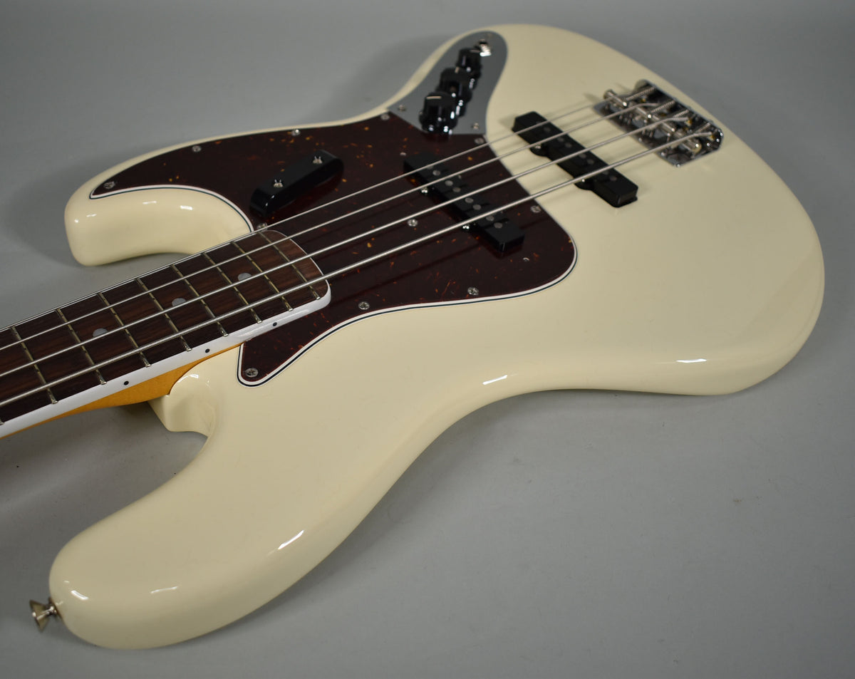 Olympic White Jazz Bass body, angled from lower bout to upper horn, showing dark tortoise pickguard and chrome hardware.