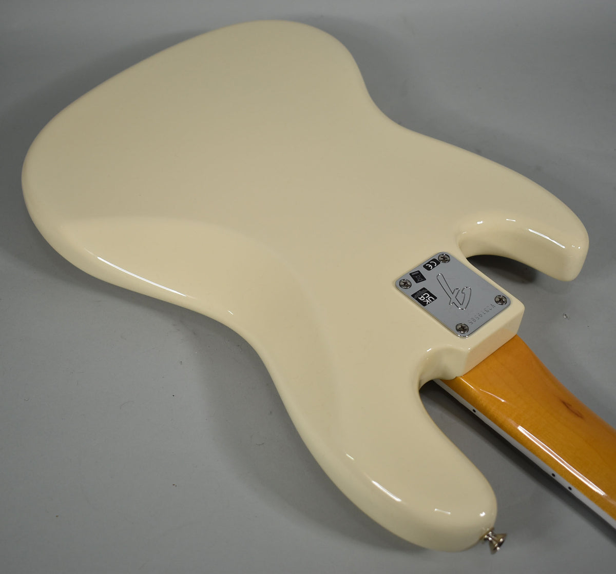 Rear view of an Olympic White Jazz Bass body with a glossy finish, showing the neck plate and a small strap button.