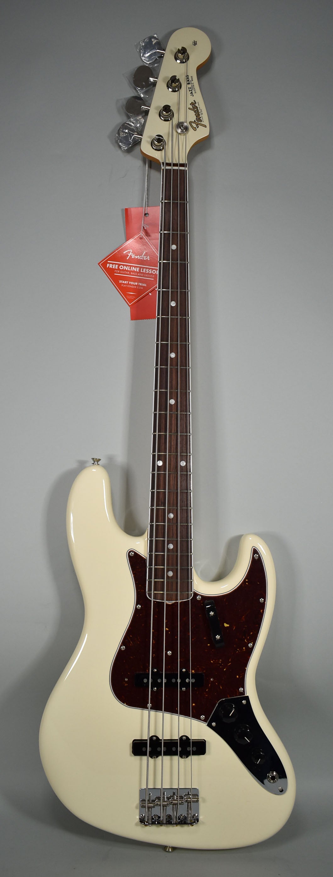 Full-length view of an Olympic White bass with a dark rosewood fretboard, tortoise pickguard, and chrome hardware.