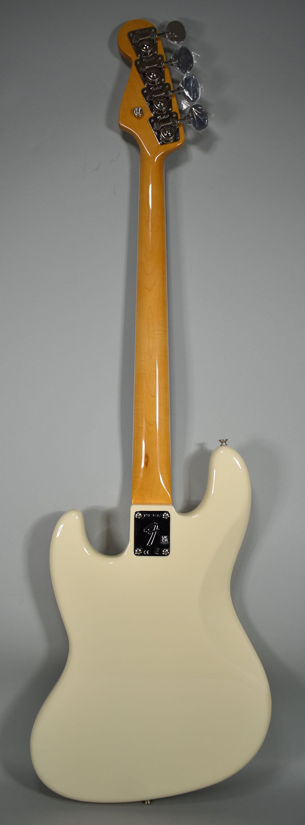 The back of an Olympic White bass with a glossy maple neck, chrome tuners, and a four-bolt neck plate.
