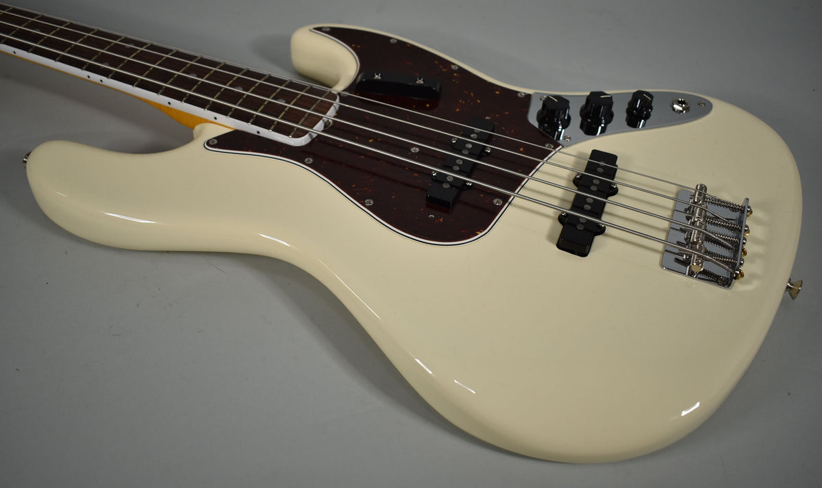 The Olympic White Jazz Bass body and neck are angled, showing the tortoiseshell pickguard, chrome bridge, and black control knobs.