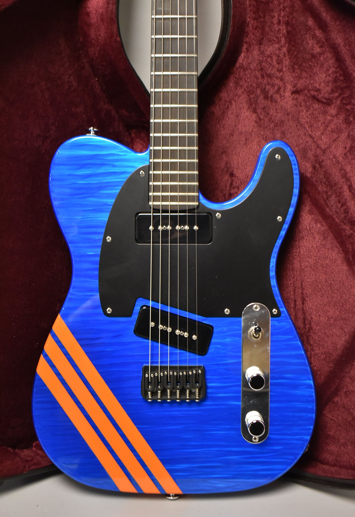 Blue flame-maple body with three orange racing stripes, black pickguard, two P-90 pickups, and chrome control plate.