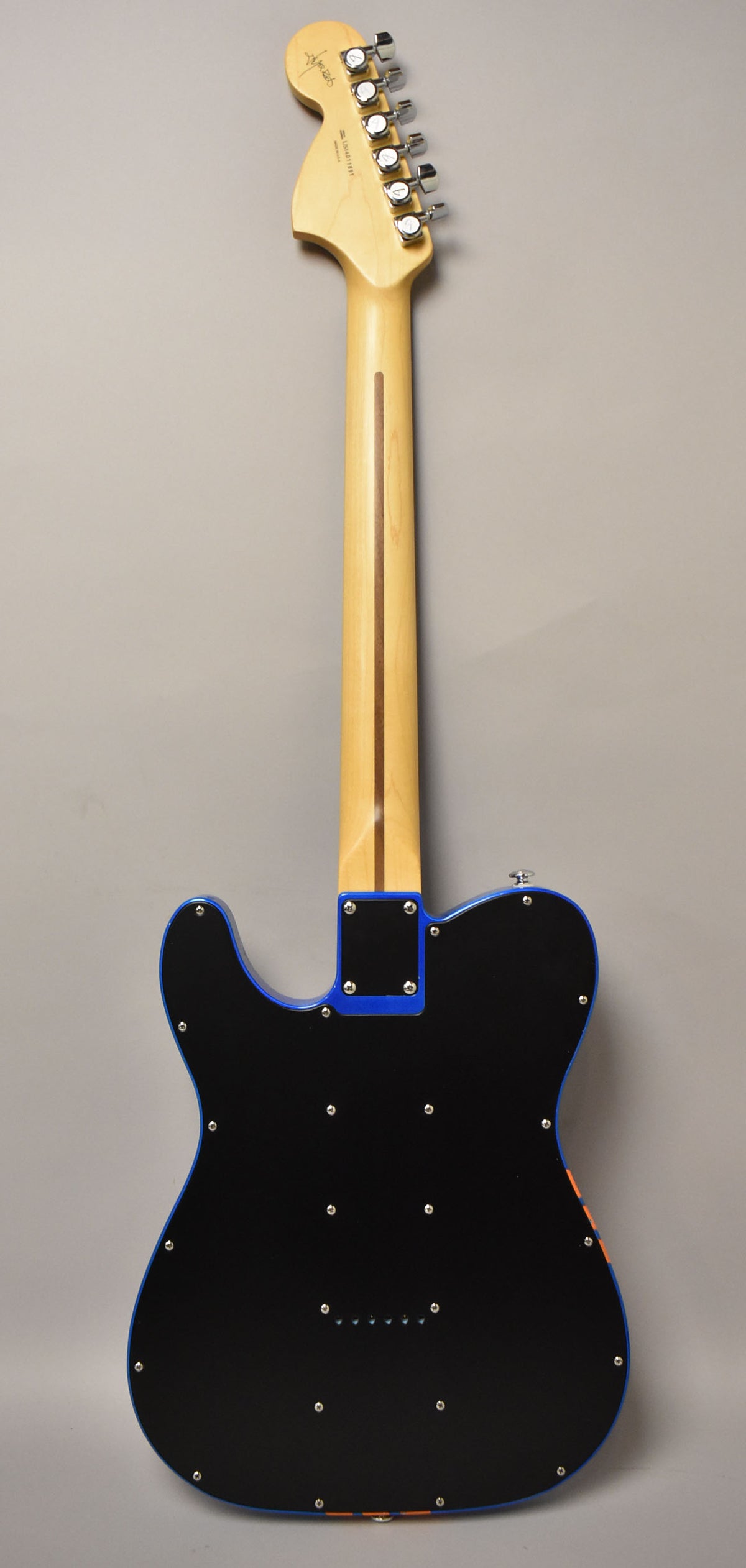 The guitar's back is black with a blue edge, revealing a natural wood neck and headstock with chrome tuners.