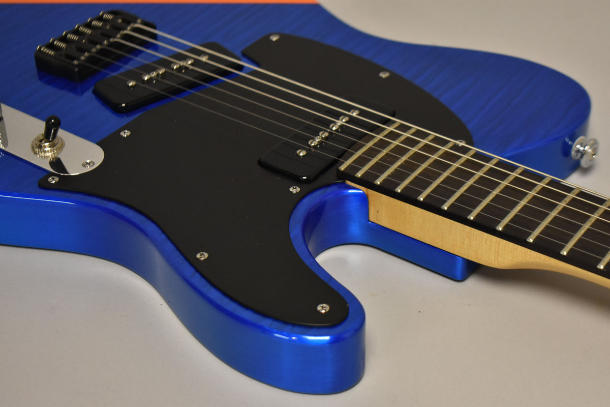 Close-up of the guitar body, showing the blue flame finish, black pickguard, two P-90 pickups, and a chrome toggle switch.