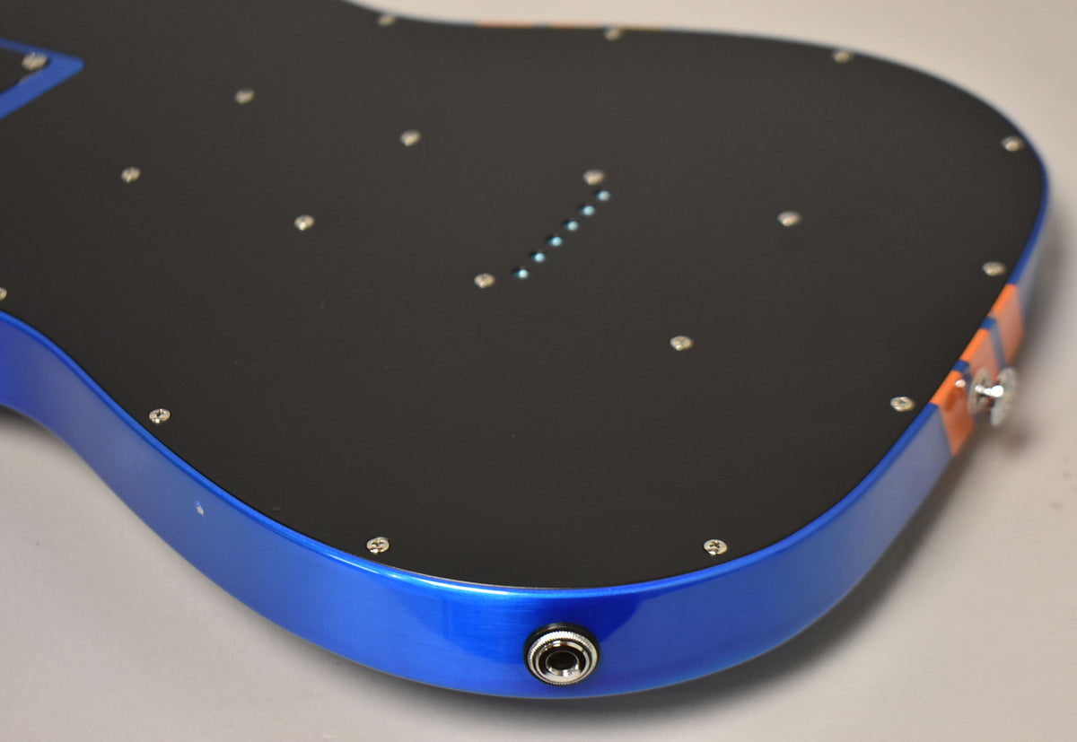 The guitar body's back is black with a blue flame finish on the sides, an output jack, and orange competition stripes.
