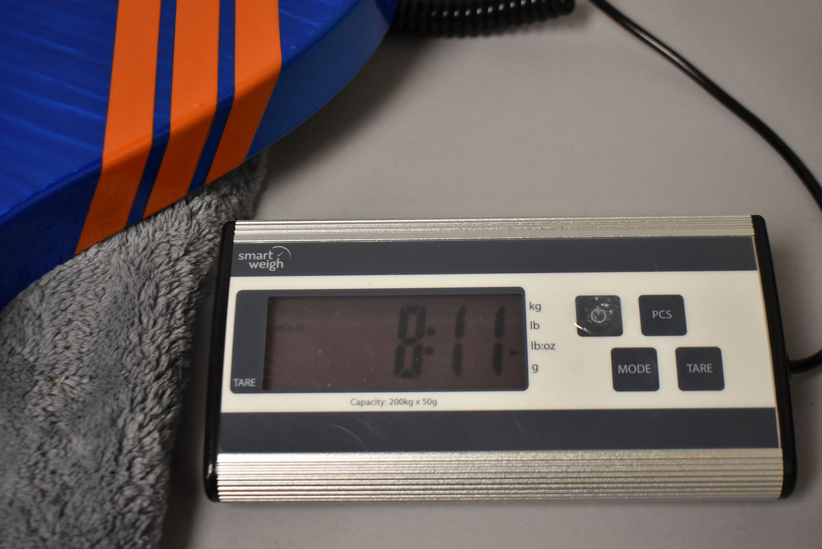 A digital scale shows the guitar's weight as 8 pounds, 11 ounces, with its blue and orange striped body partially visible.