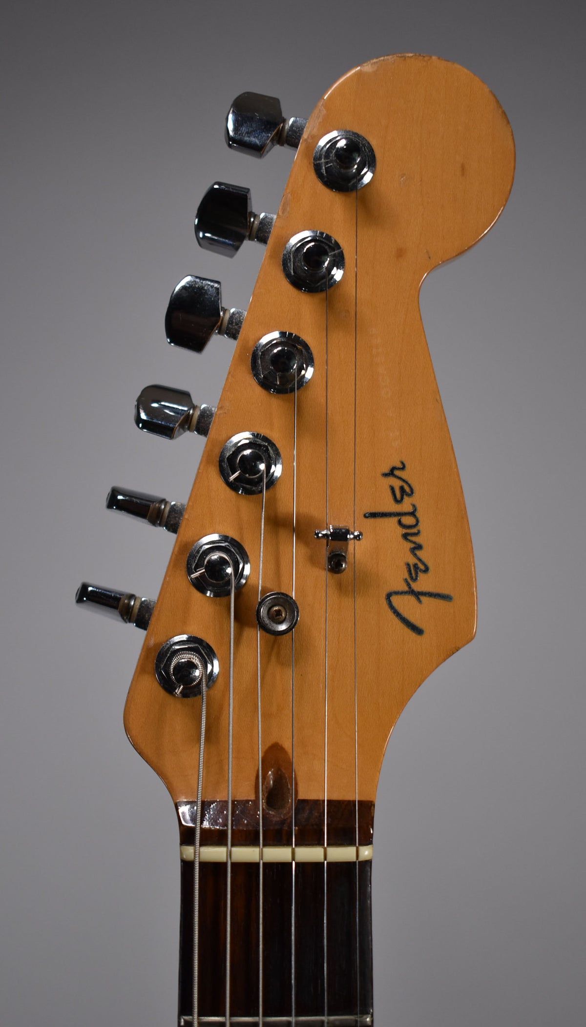 Close-up of the guitar's headstock, showing six chrome tuners, a string tree, and a dark rosewood fretboard with a bone nut.
