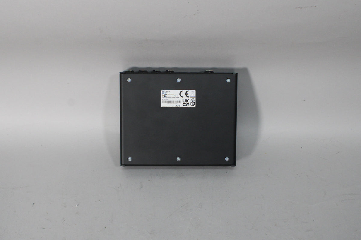 The black pedal modeler is viewed from the bottom, showing a large white label with regulatory marks and six silver screws.