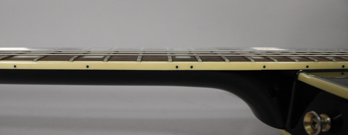 Close-up of the black gloss neck and cream-bound fretboard with dark fret markers, showing some light wear on the binding.