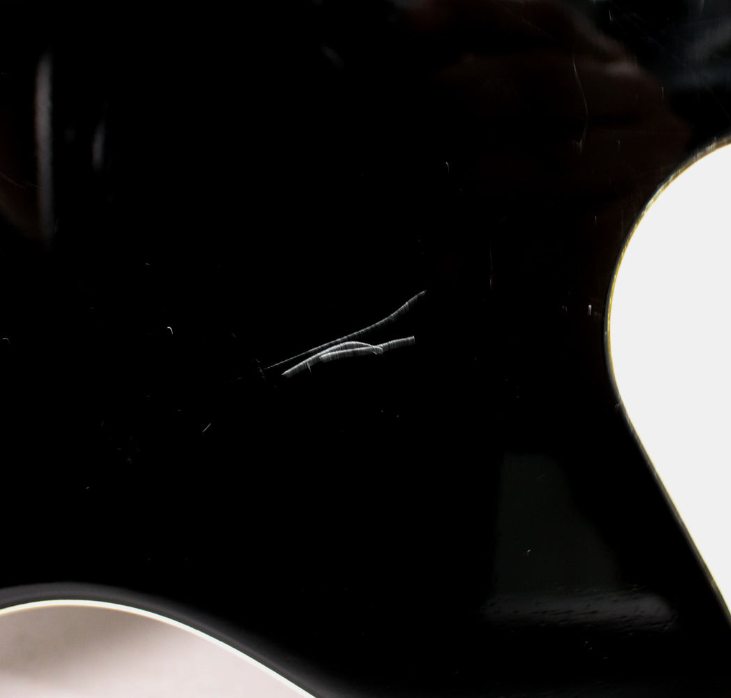 Close-up of the black gloss body with visible scratches and scuffs, highlighting the wear on the finish.