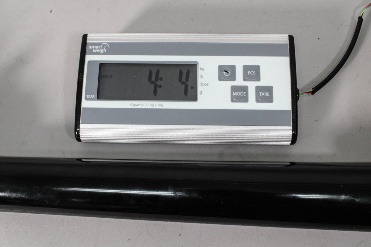 A digital scale displays "4.4" with a black guitar neck resting below it, showing minor surface wear on its glossy finish.