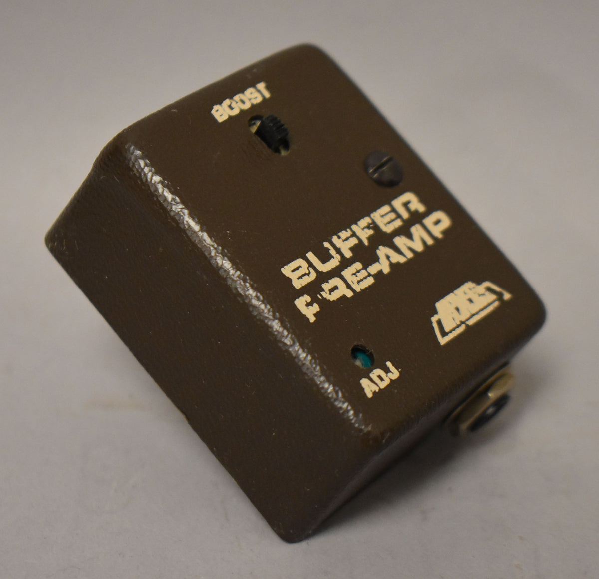 A brown AXE Model BPA-1 Buffer Pre-Amp pedal with "BOOST" and "ADJ" labels, a switch, and a jack.