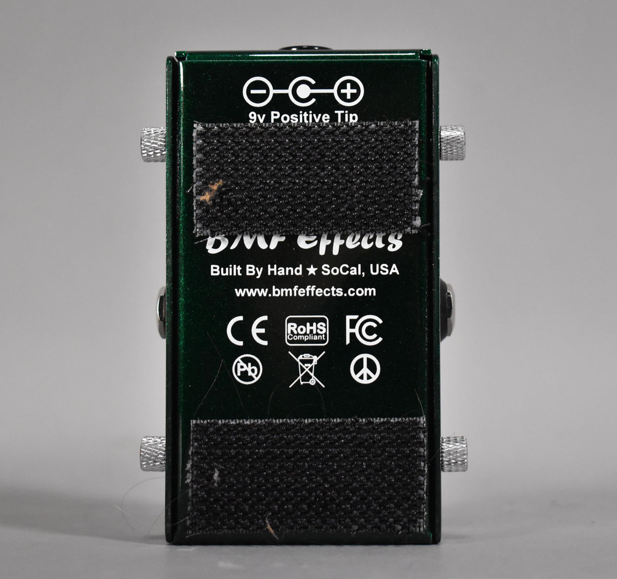 The dark green pedal's back panel is visible, covered by two strips of black hook-and-loop fastener with some visible wear.