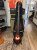 Full-length view of a tobacco sunburst acoustic-electric bass with a black gig bag, standing on a rug in a guitar shop.