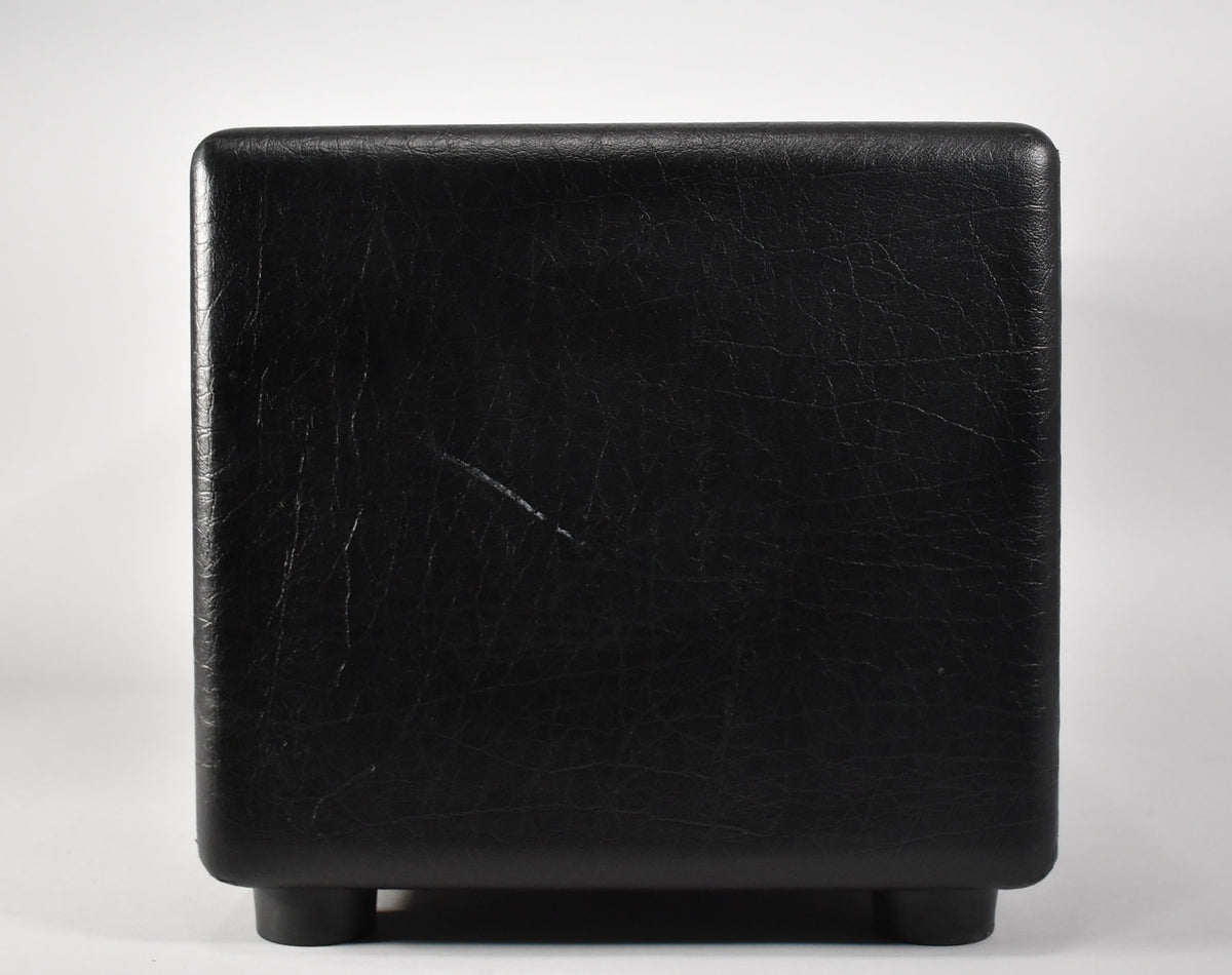 Rear view of a black amplifier head with textured covering and four rubber feet, showing minor scuffs.