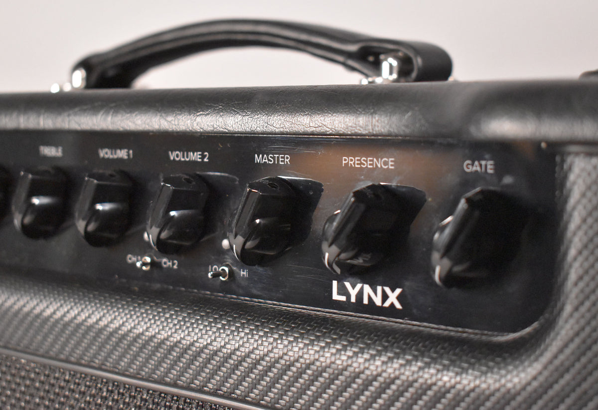 Close-up of the black amp's control panel, showing six black knobs for Treble, Volume 1, Volume 2, Master, Presence, and Gate.