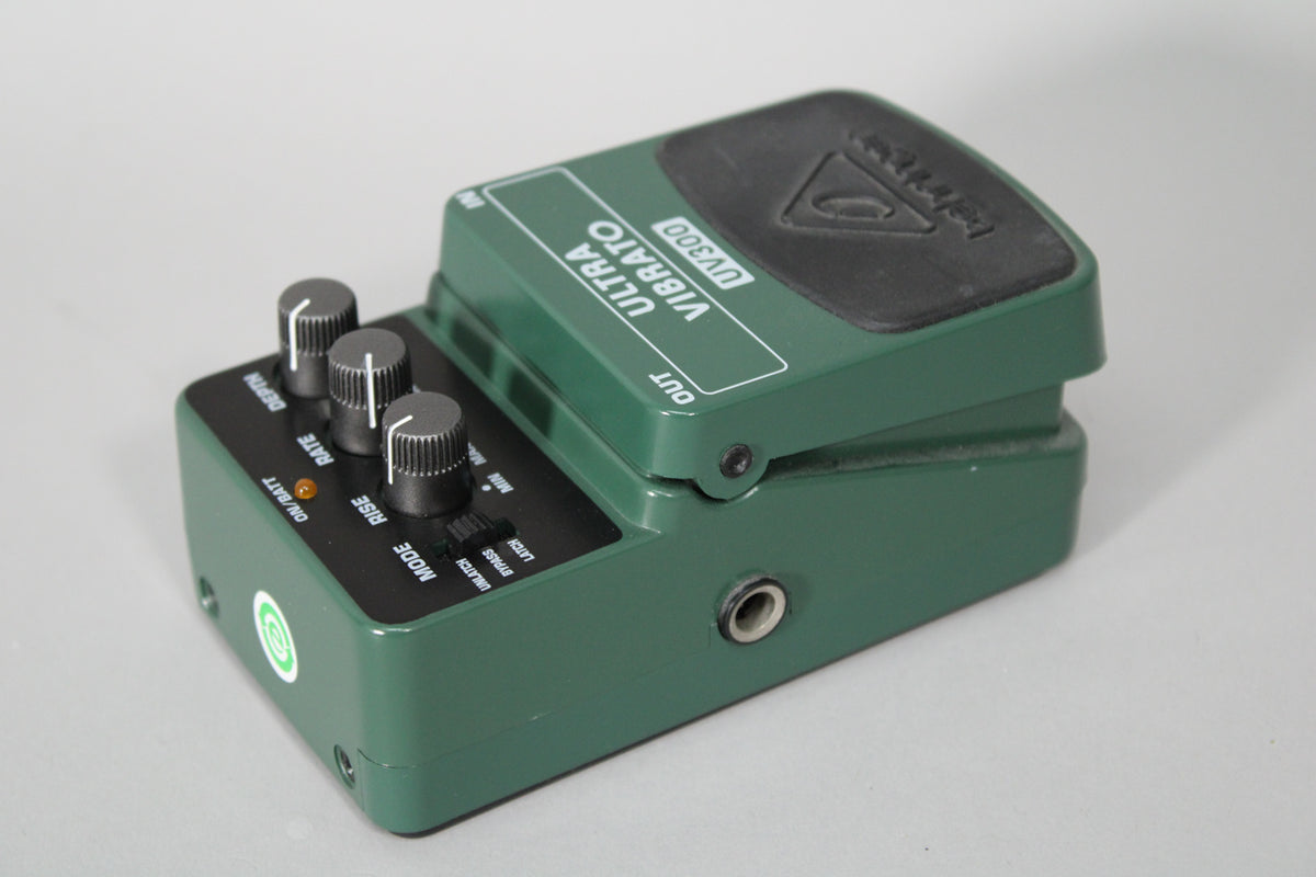 A dark green vibrato pedal, viewed from the right, showing three black control knobs and a small input jack.