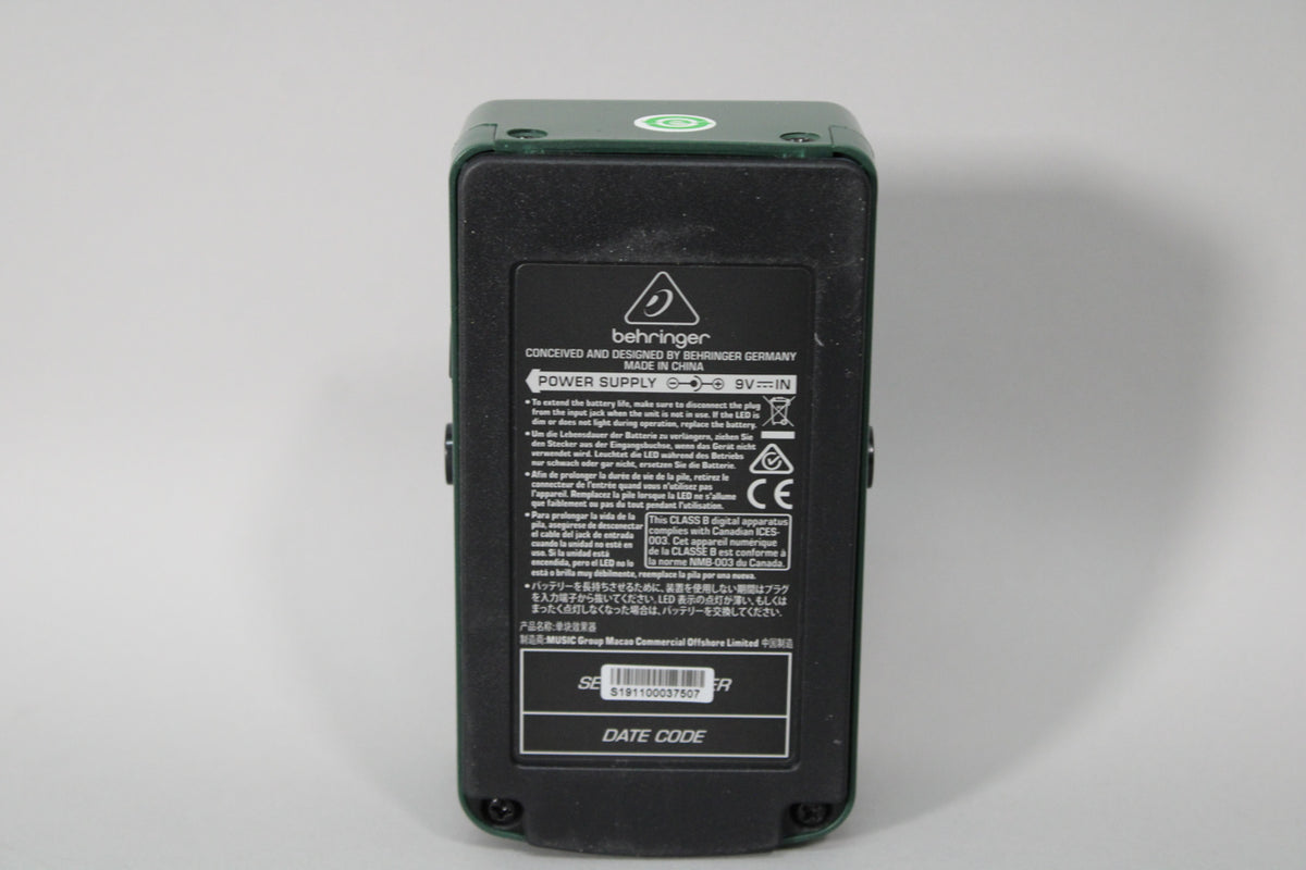 The dark green pedal is viewed from the back, showing a black label with white text and a barcode.