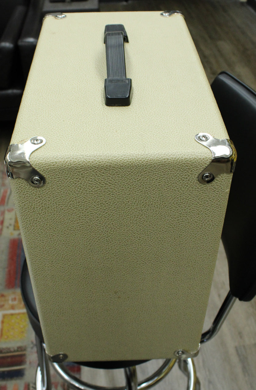 Top-down view of a blonde extension cab with a black handle and chrome corner protectors, sitting on a stool.