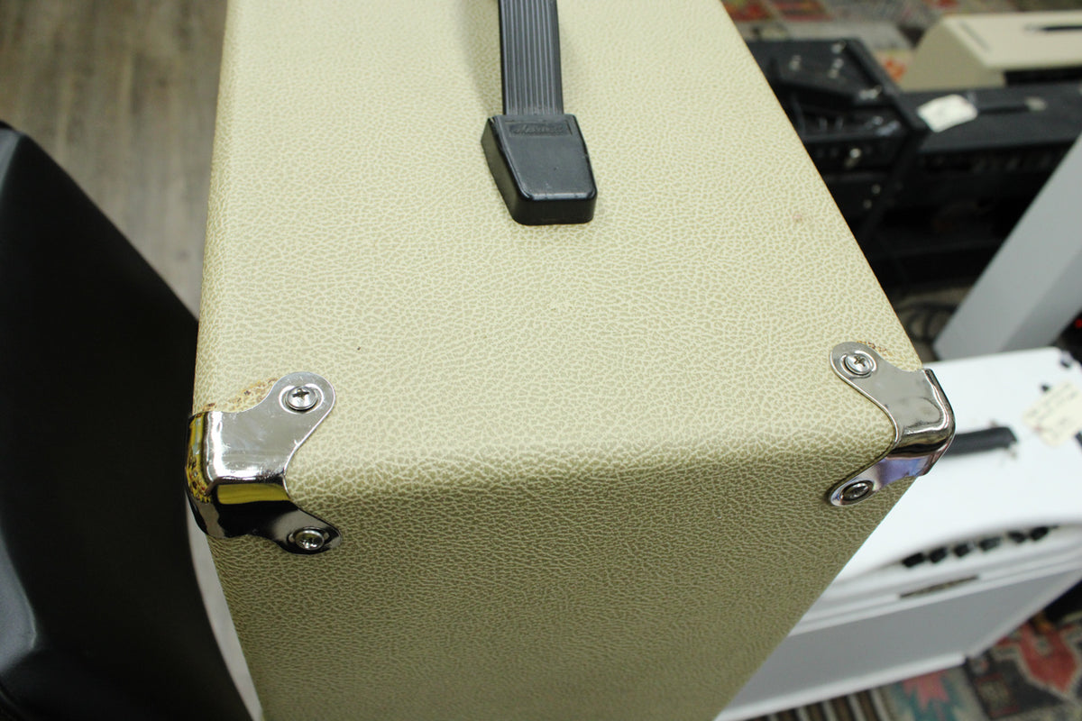 Top-down view of the blonde textured cab, showing the black handle and two shiny metal corner protectors with minor scuffs.