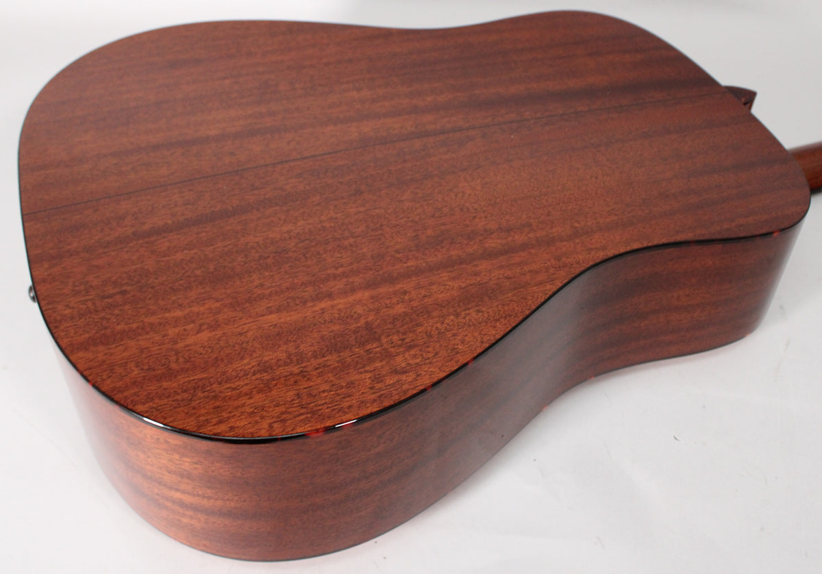 The back and side of a dreadnought acoustic guitar, showing the reddish-brown mahogany wood grain with a glossy finish.