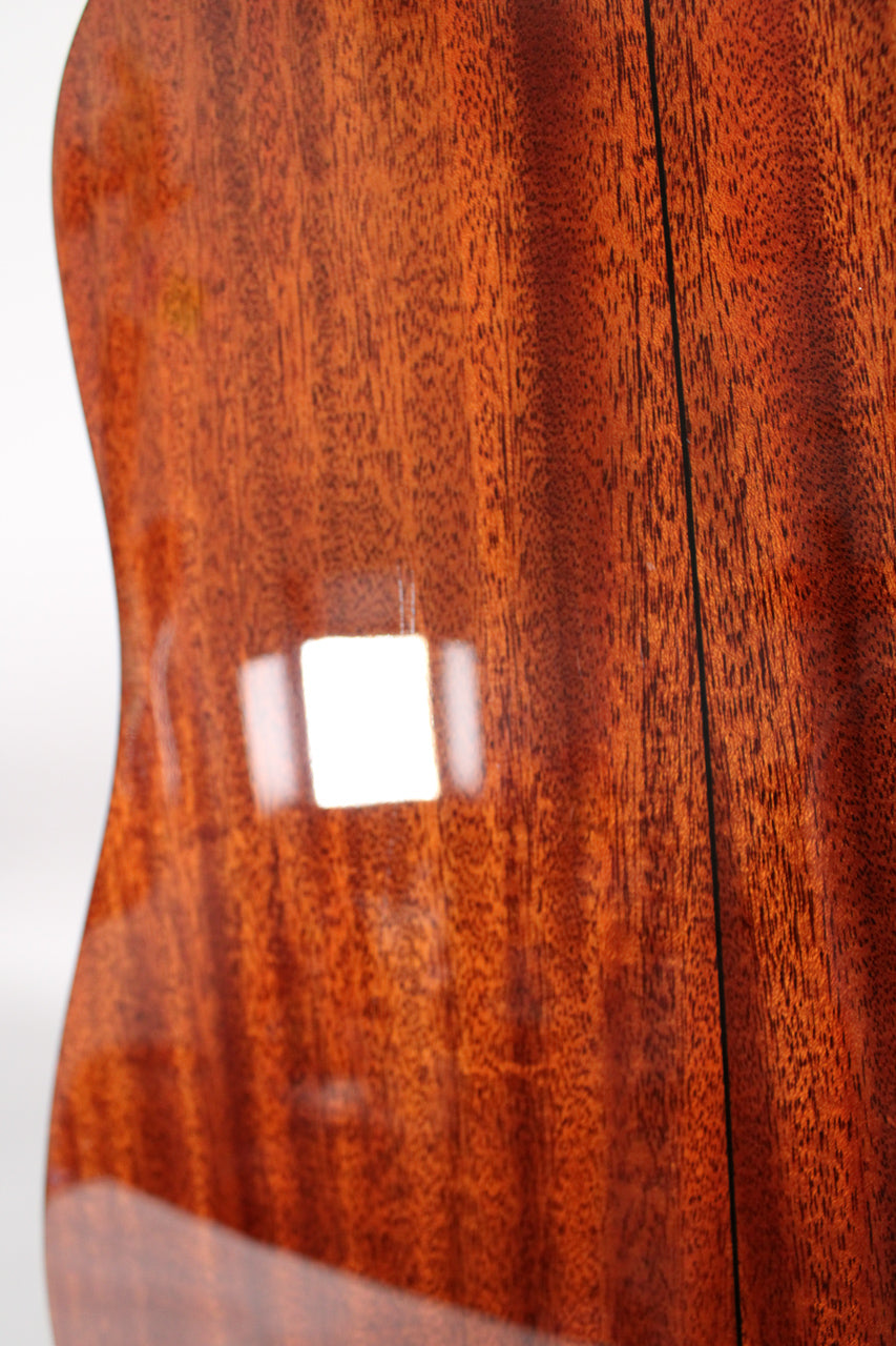 Close-up of the guitar's glossy, reddish-brown mahogany back, showing wood grain and a dark center seam.