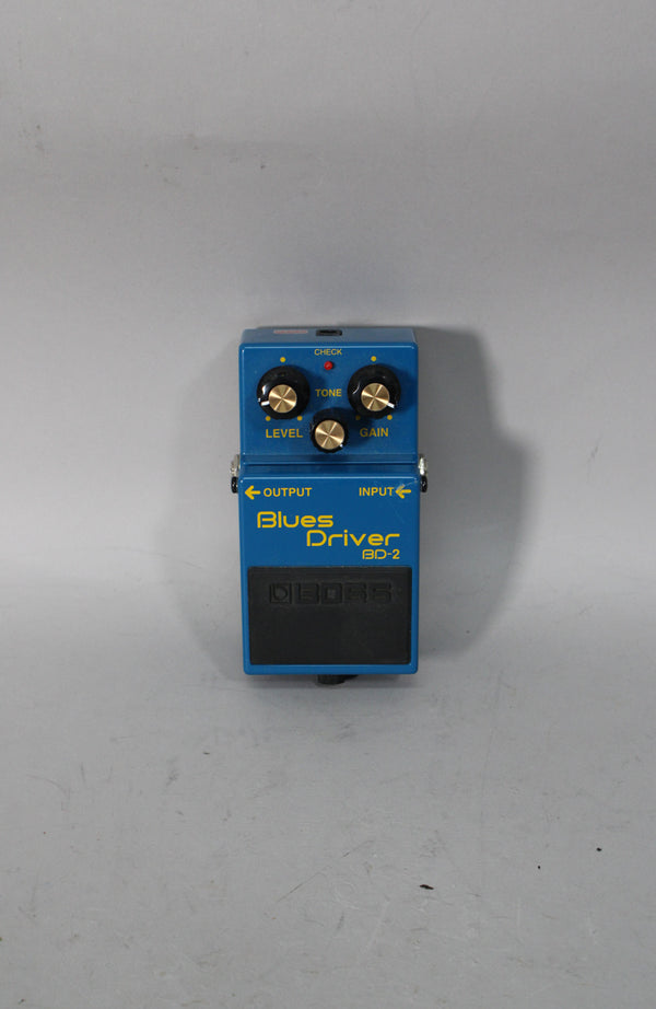 A blue guitar pedal with three gold-capped black knobs, a red LED, and a black rubber footpad, viewed from above.