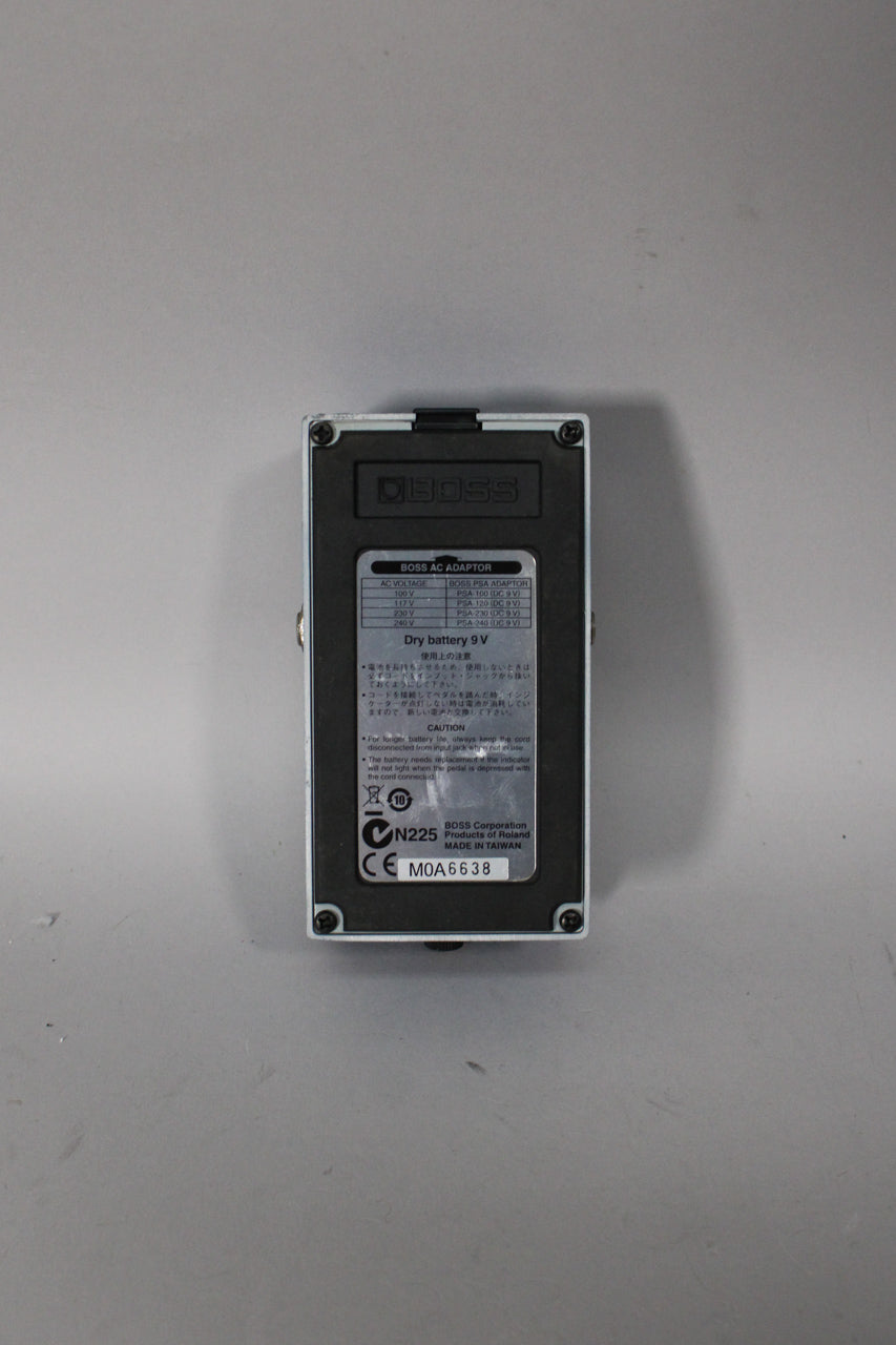 The pedal's gray metal baseplate is shown, with a black label displaying text and a serial number.