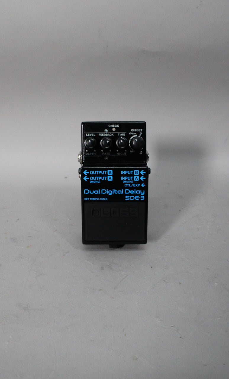 Black rectangular pedal, viewed from above, with blue lettering and four black knobs on the top panel.