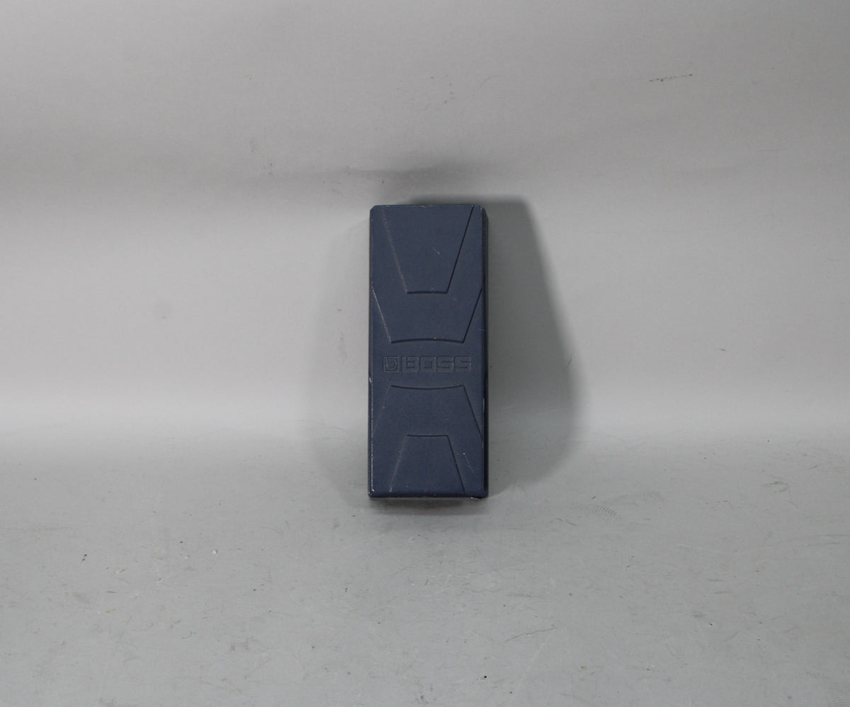 A dark gray expression pedal, viewed from above, with a textured surface and a subtle logo embossed in the center.