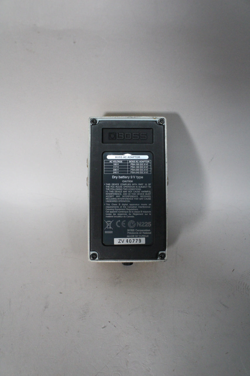 The pedal's off-white base is seen from the back, with a black rectangular plate covering most of the surface, secured by four screws.