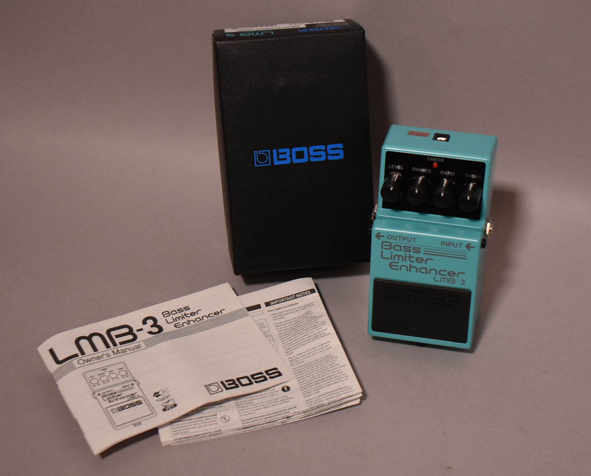 A teal pedal with four black knobs and a black footswitch, shown with its black box and owner's manual.